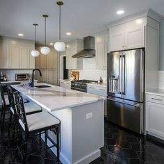 a large kitchen with white cabinets and marble counter tops, stainless steel appliances and black tile flooring