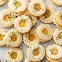 small crackers with oranges and rosemary on top are arranged in rows, ready to be eaten