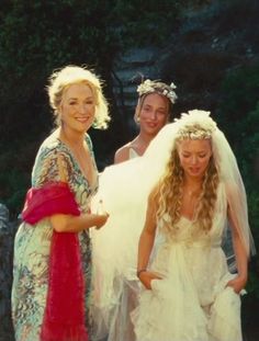 three women in wedding dresses standing next to each other and one is wearing a veil