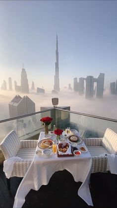 a table with food and drinks on top of a building in the foggy city