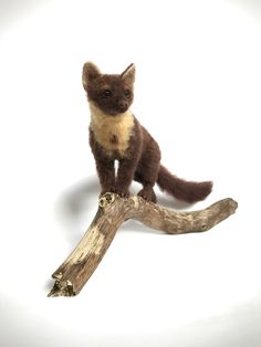 a small stuffed animal sitting on top of a wooden branch next to a white background