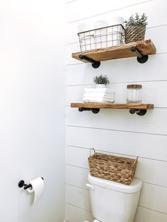 a white toilet sitting next to a wooden shelf