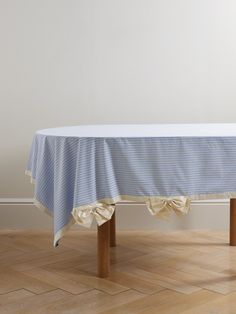 a blue and white striped tablecloth on a wooden table in an empty room with hard wood flooring