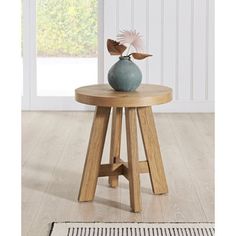 a small wooden table with a vase on it and a rug in front of it