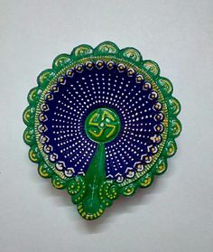 a green and blue decorative object on a white surface