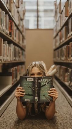 a woman laying on the floor reading a book in a library with bookshelves behind her