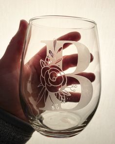 a hand holding a wine glass with the letter b etched on it's side