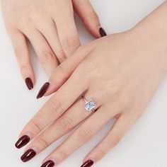 a woman's hand with red nail polish holding a diamond ring