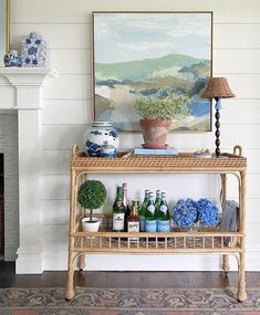 a wicker shelf with bottles and vases on it in front of a fireplace