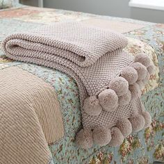 a blanket with pom - poms on it sitting on top of a bed