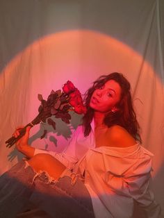 a woman sitting on the floor with roses in her hand