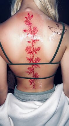 the back of a woman's body covered in tattoos with roses painted on it