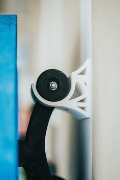 a black and white object is hanging on the wall next to a blue door handle