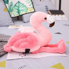 a pink stuffed flamingo sitting on top of a bed