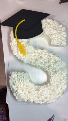 a graduation cap and gown shaped cake sitting on top of a white tablecloth covered box