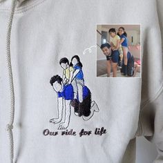 a white sweatshirt with an image of two people and a child on the front, one woman is holding a baby