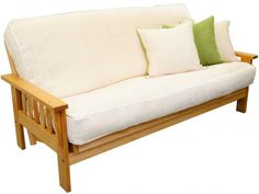 a white couch with two green pillows on it's back and one in the front