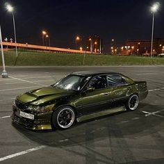 a green car parked in a parking lot at night