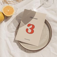 the table is set with two oranges and a card that says 3 on it