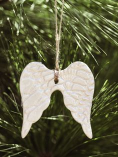 an angel wing ornament hanging from a pine tree