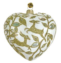 a white and gold heart shaped ornament with deers on the front, surrounded by leaves