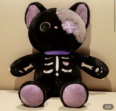 a black and white cat stuffed animal sitting on top of a table next to a wall