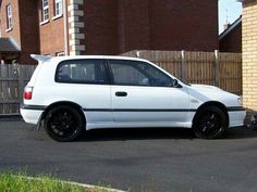 a white car parked in front of a brick building