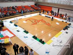 an indoor basketball court with people standing around it