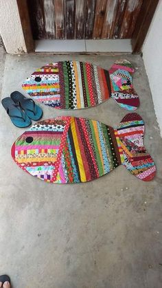 two pairs of flip flops are laying on the floor next to a fish shaped rug