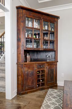 a large wooden cabinet with glass doors and shelves in the middle of a living room