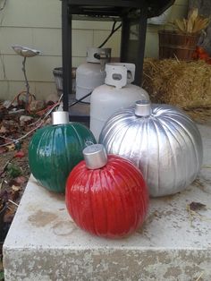 three metal pumpkins sitting on top of a cement block