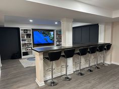 an entertainment room with bar stools and a flat screen tv mounted on the wall