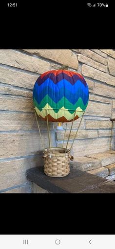 a colorful hot air balloon sitting on top of a wooden table next to a brick wall