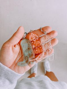 a person holding two keychains in their hands, one with an intricate design on it