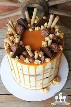 a cake decorated with chocolate, nuts and caramel drizzles on a white plate