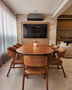 a dining table with six chairs and a television mounted on the wall in front of it