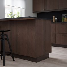 a modern kitchen with an island and bar stools in the center, along with dark wood cabinetry