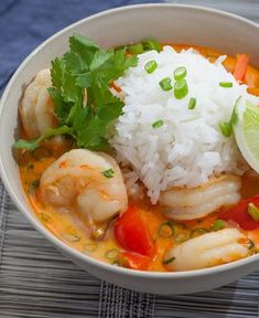 a white bowl filled with shrimp, rice and cilantro on top of a table