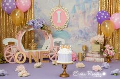 a birthday cake and decorations on a purple table with gold sequins, pink flowers and balloons