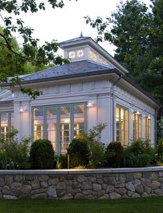 a white house sitting on top of a lush green field next to a stone wall