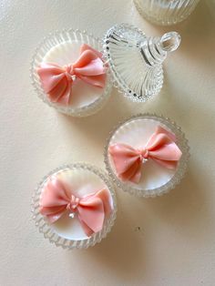 three little bows are in small glass dishes on the table, one pink and one white