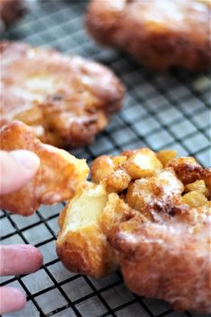 a person is picking up some doughnuts from a cooling rack