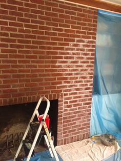 a man is painting a brick fireplace with blue tarp on the wall and a ladder