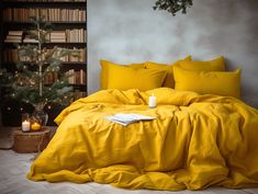 a bed with yellow sheets and pillows next to a christmas tree