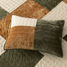 two brown and white pillows sitting on top of a quilted bed cover with an orange stripe down the middle