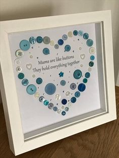 a white frame with buttons in the shape of a heart on top of a wooden table