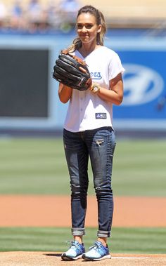 a woman standing on top of a baseball field holding a catchers mitt