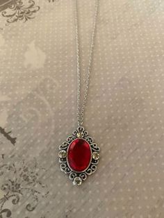 "This pretty oval shaped necklace in tibetan silver and red has an intricately designed edging with a red crystal center stone and 4 side rhinestone accents.  Pendant measures 1 3/8\" L X 1\" W and is on an 18\" chain.    ★ Want to see more?  Please visit my shop at: https://www.etsy.com/shop/DesignsByPeg" Red Stone Pendant, Red Gemstone Necklace, Red Stone Jewelry, Red Pendant Necklace, Red Stone Necklace, Red Crystal Necklace, Red Pendants, Red Necklace, Necklace Red