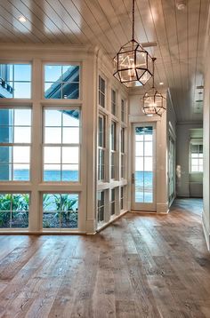 the inside of a house with large windows and doors leading to an ocean front yard