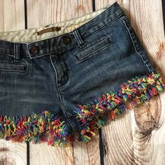 a pair of denim shorts with multi - colored fringes on the bottom and sides